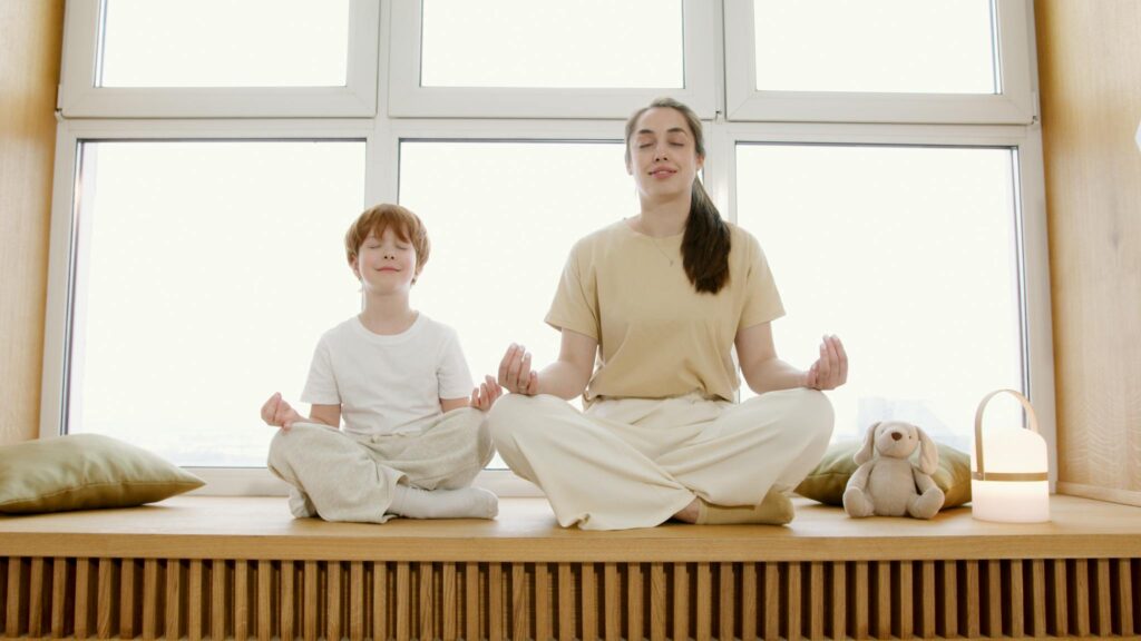 Mother and son practicing yoga poses indoors, reflecting calmness and family bonding.